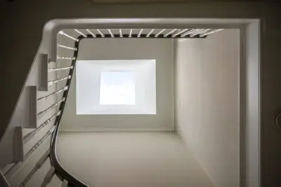 View looking up a modern staircase with a large square rooflight illuminating the stairwell.